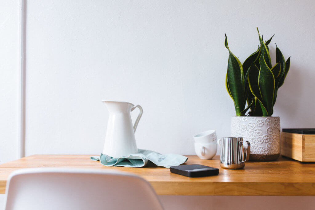 A photo of a wooden desk with coffee accessories and a smartphone